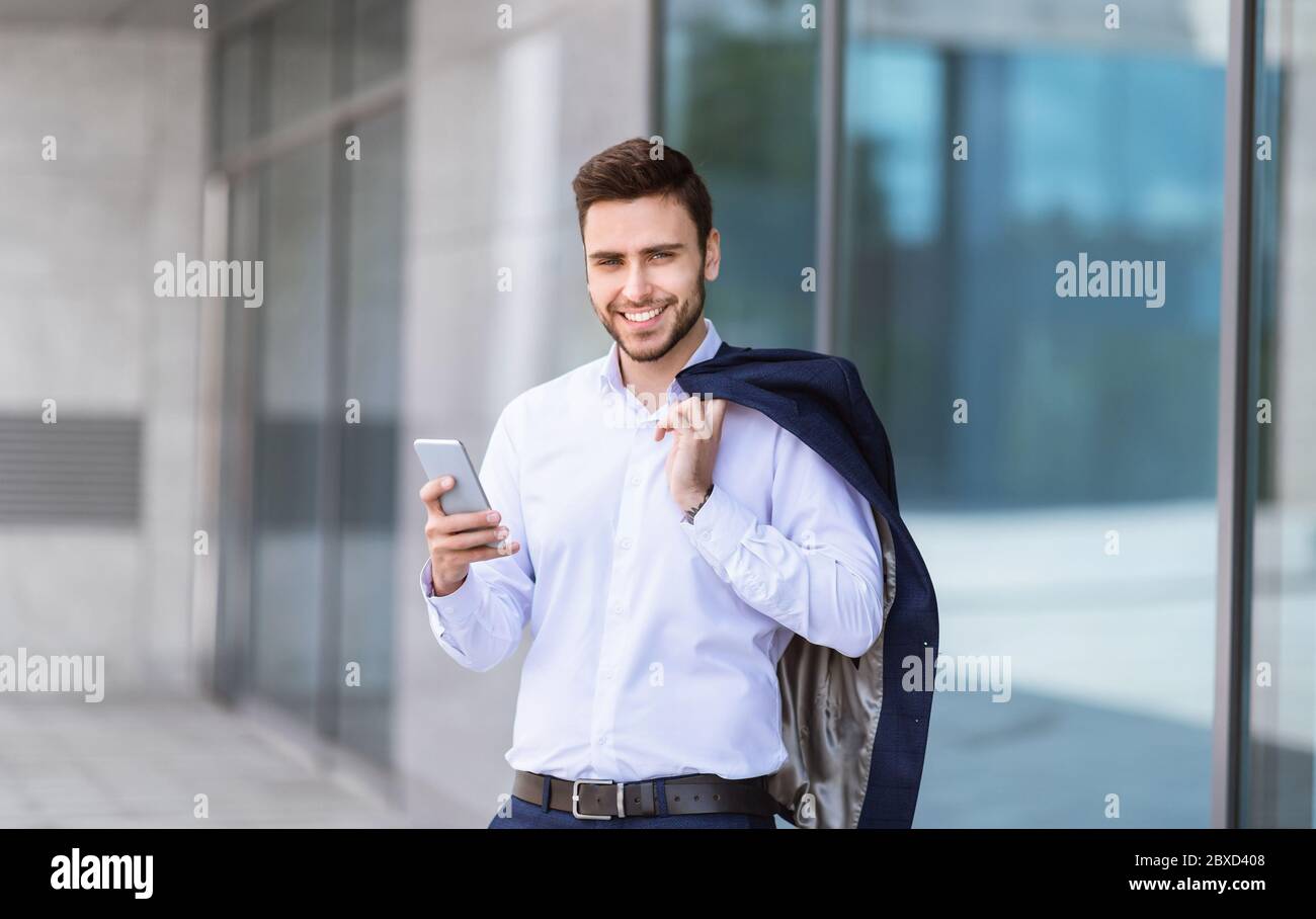 Glückliche Business-Agent mit mobilen Gerät vor Wolkenkratzer im Freien Stockfoto