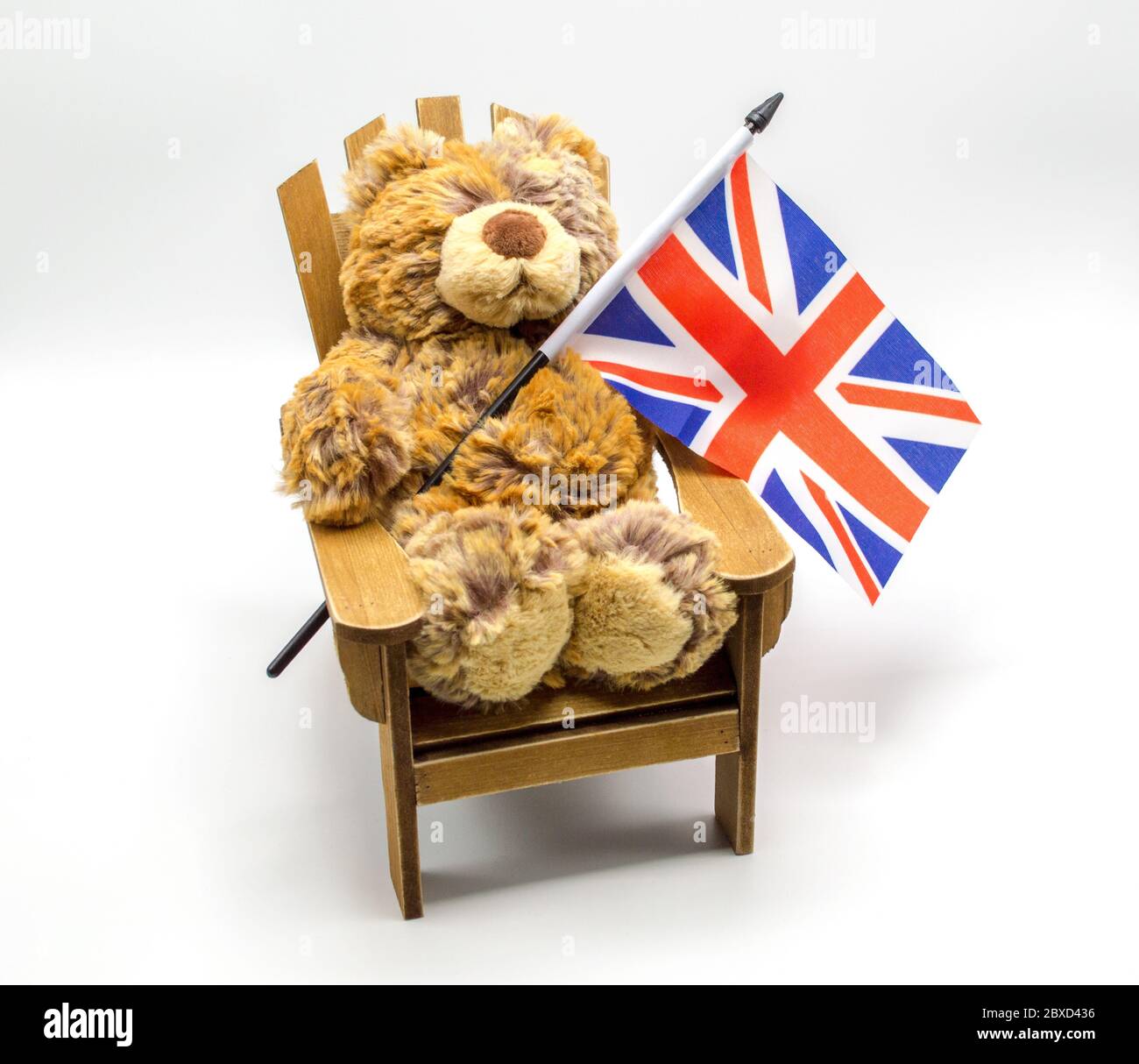 Kuscheltier Bär sitzt in einem Adirondack Stuhl mit einer kleinen British Union Jack Flagge isoliert auf weiß Stockfoto