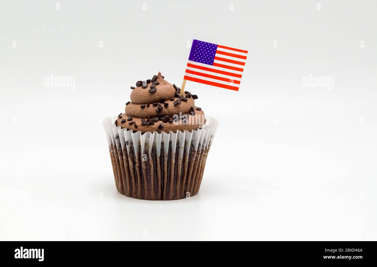 Ein butterhaltiger Schokoladenchip Cupcake mit einem Zahnstocher der amerikanischen Flagge, der auf Weiß isoliert ist Stockfoto