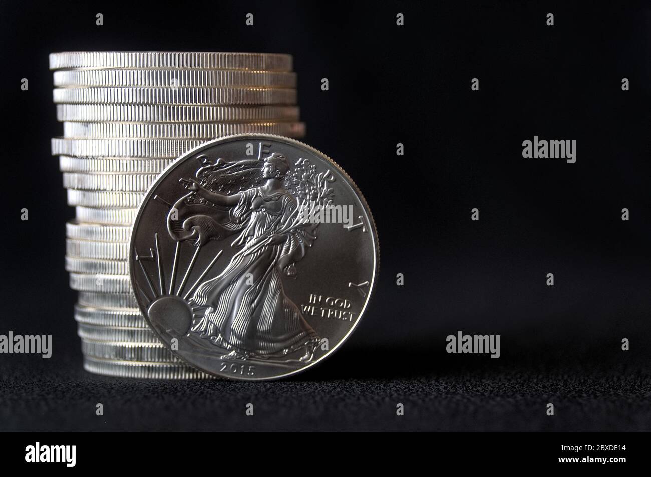 Eine glänzende neue amerikanische Silberadlermünze vor einem Stapel ähnlicher Silberadlermünzen Stockfoto