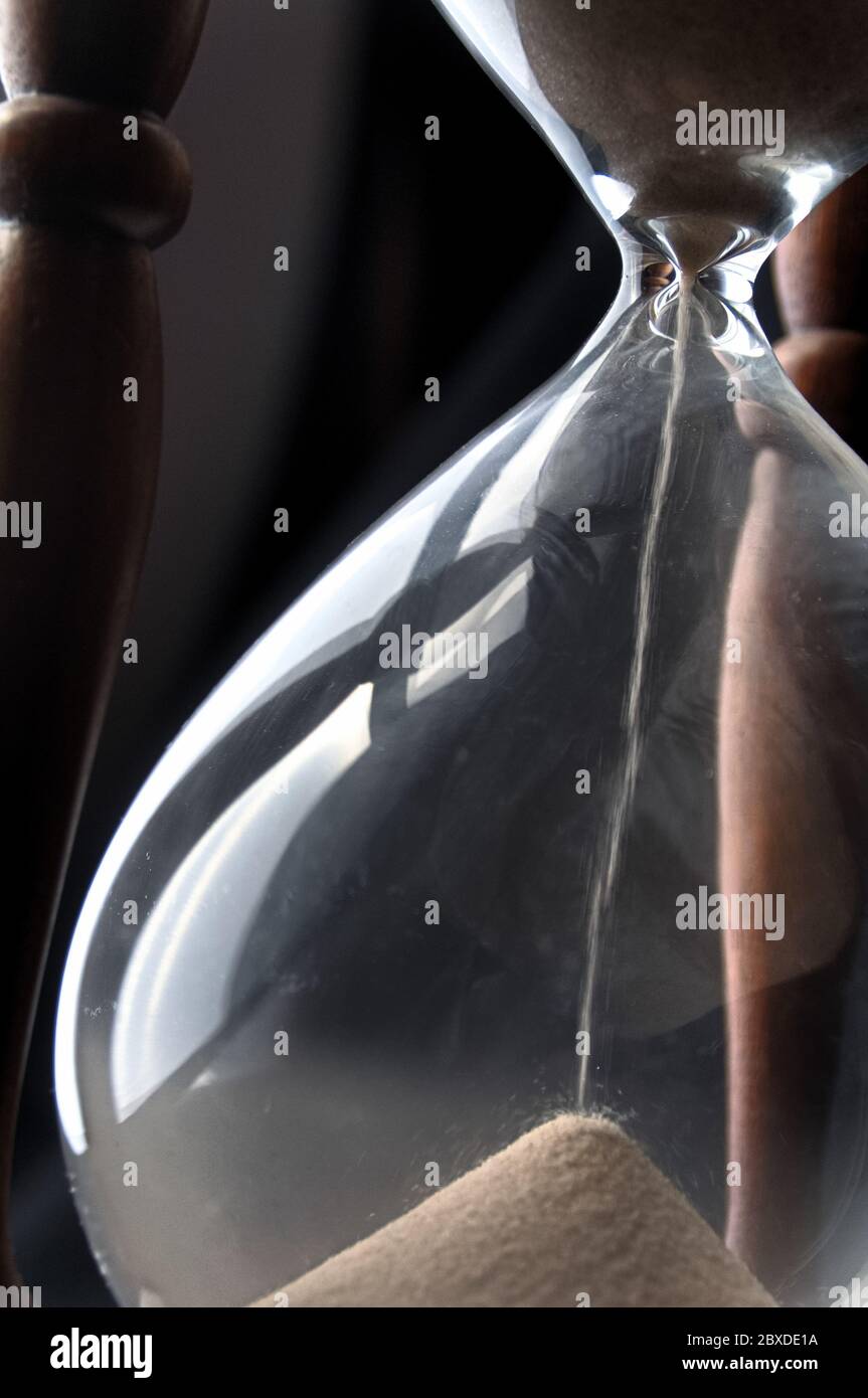 Nahaufnahme von schrägem Blick auf Sand, der durch eine Sanduhr geht, mit natürlichem Licht Stockfoto