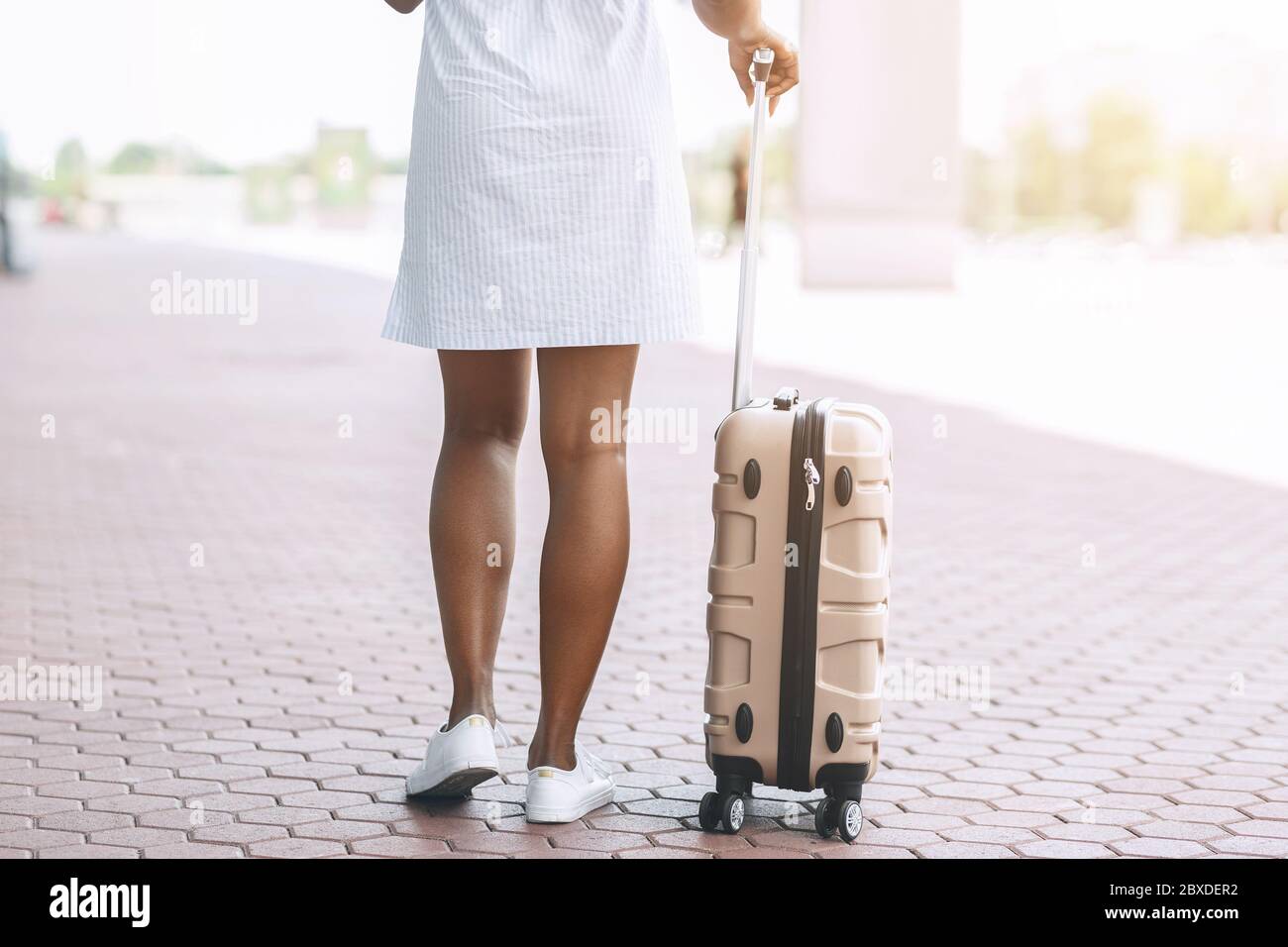 Warten auf Übertragung. Schwarze Frau steht mit Gepäck am Flughafen Parkplatz Stockfoto