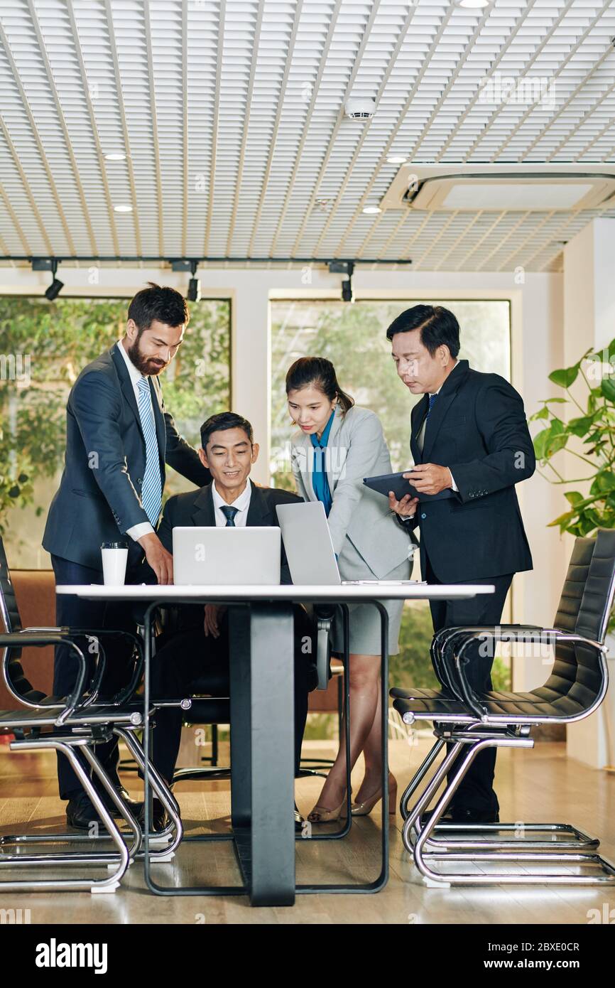 Das multiethnische Geschäftsteam hat sich am Bürotisch versammelt, um die Ergebnisse der produktiven Arbeit zu besprechen Stockfoto