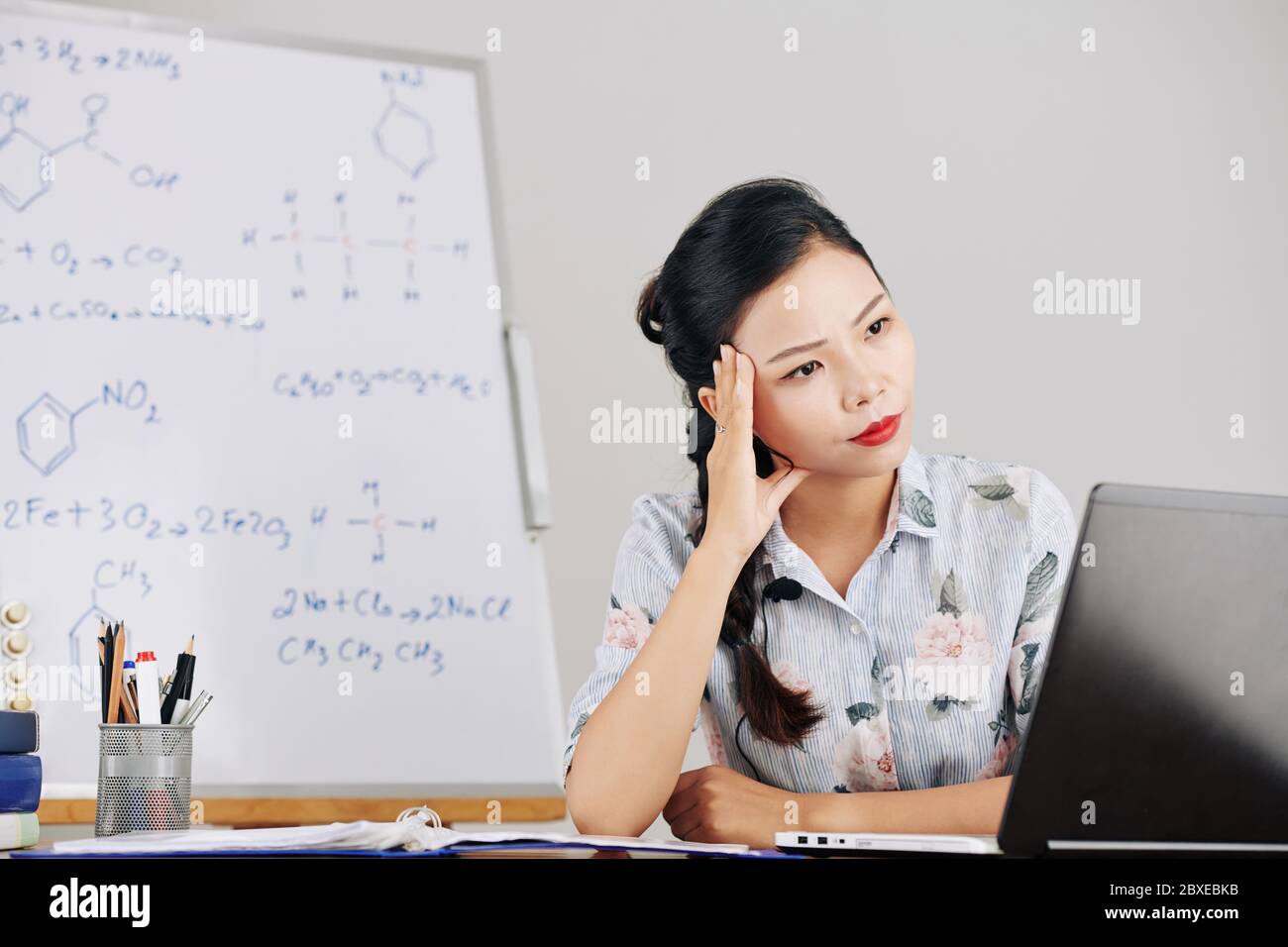 Nachdenkliche junge Lehrerin für Naturwissenschaften, die denkt, wie sie während einer Pandemie Chemieunterricht für ihre Schüler durchführen kann Stockfoto
