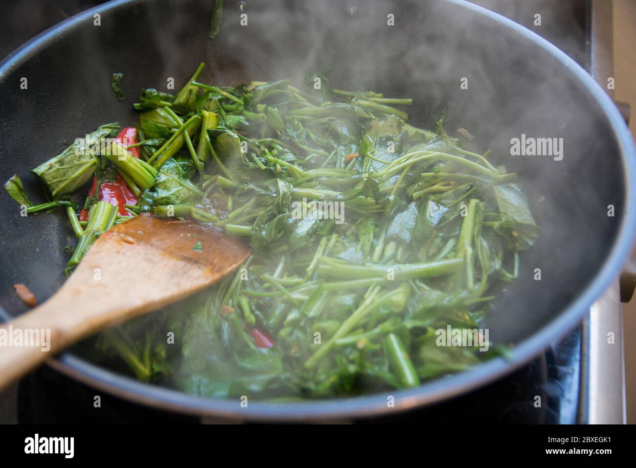 'Pad Pak Boong' ein traditionelles thailändisches Gericht: Gebratenes 'Morning Glory' Gemüse (Ipomoea aquatica), im Wok gegrillt Stockfoto