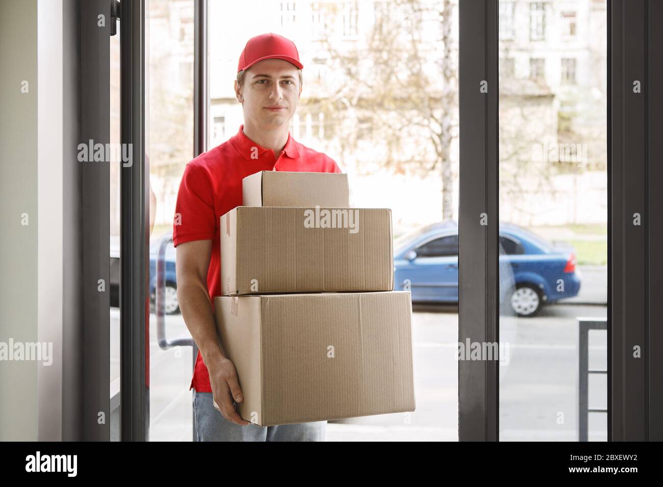 Online-Shopping ohne zu Hause und schnelle Lieferung. Kurier in Uniform hält Pappkartons Stockfoto
