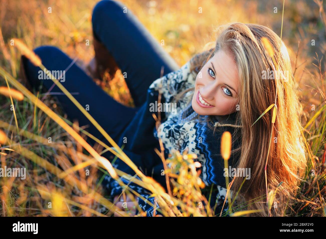 Schöne blaue Augen Mädchen mit Wollpullover in einem Feld. Warmes Licht bei Sonnenuntergang Stockfoto