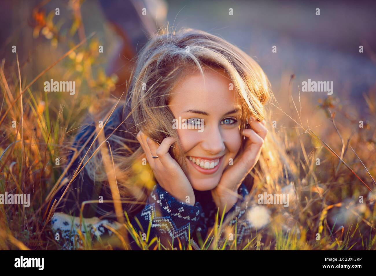 Schöne glückliche Frau lächelt entspannend auf Gras. Herbstfarben Stockfoto