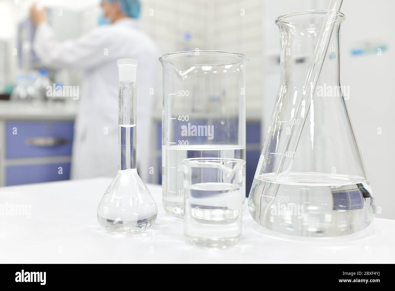 Blur-Wissenschaftler, der in einem Chemistry Science-Labor mit Kolben, Becher und Glaswaren arbeitet, die klare flüssige Chemikalien enthalten. Stockfoto