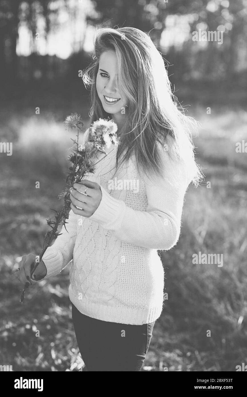 Schöne junge Frau posiert in einem Feld mit trockenen Blumen Stockfoto