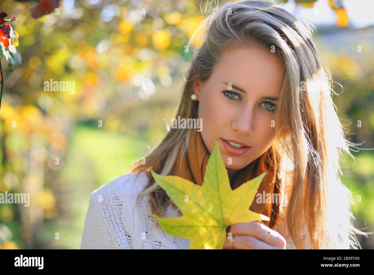 Schöne junge Frau mit Herbstblatt. Saisonales Porträt Stockfoto