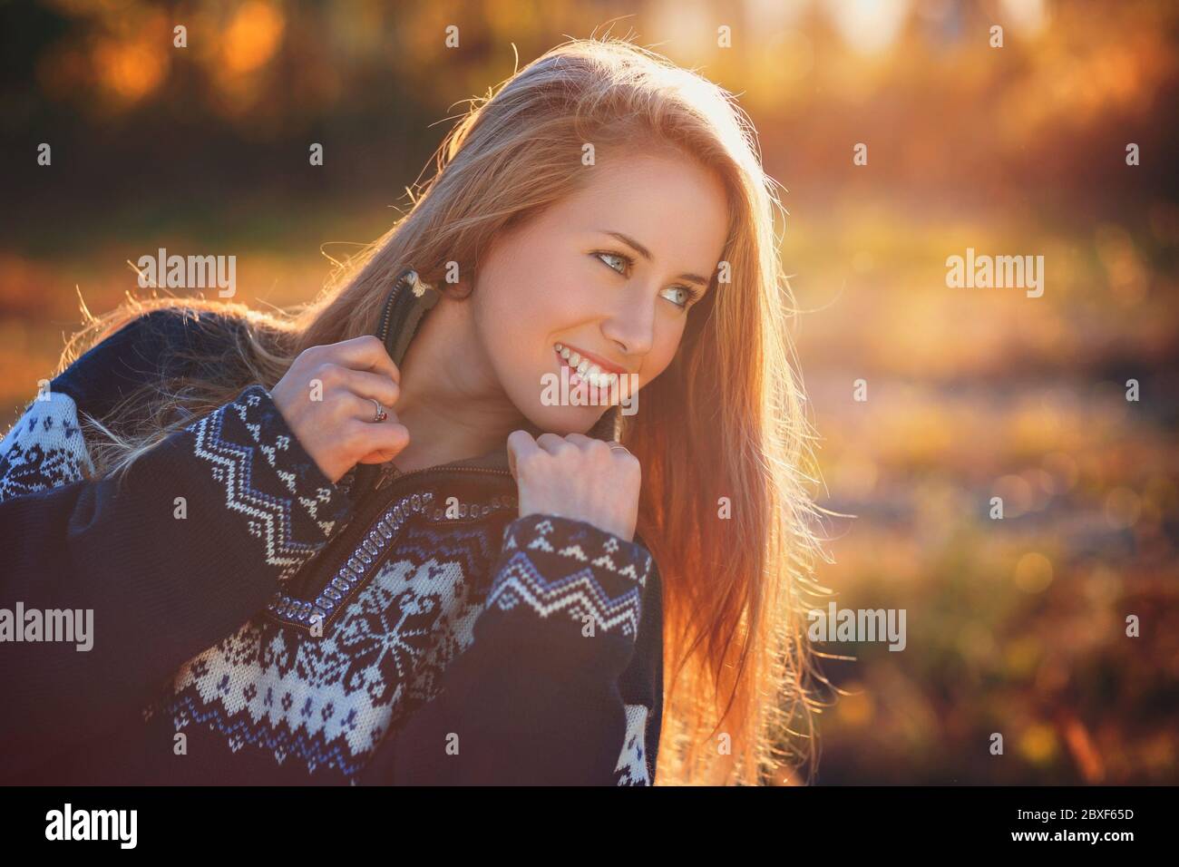 Lächelnd schönes Mädchen posiert mit schweren Pullover im Sonnenlicht. Herbstfarben Stockfoto