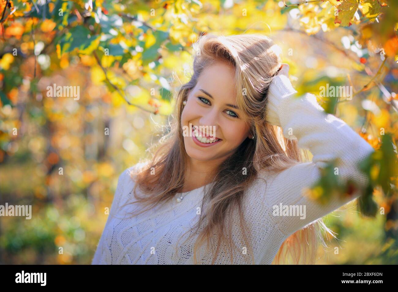 Schöne lächelnde Mädchen in warmen Herbstfarben. Porträt mit saisonaler Hintergrundbeleuchtung Stockfoto