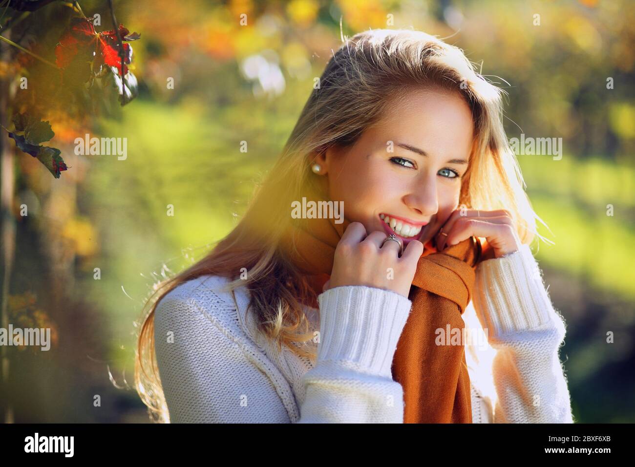 Schöne lächelnde Frau in warmen Herbstlicht. Porträt mit saisonaler Hintergrundbeleuchtung Stockfoto