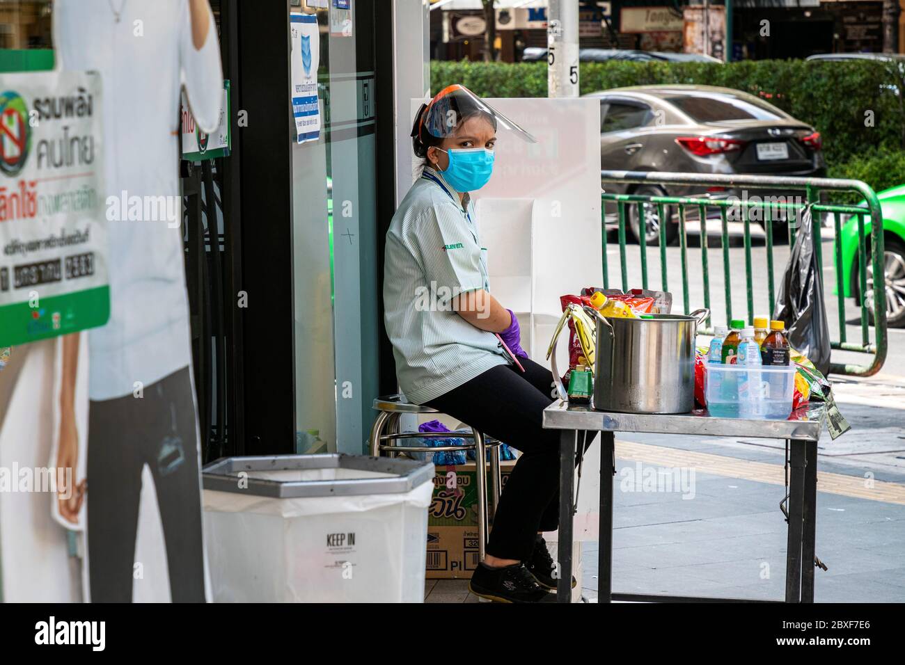 Shop Mitarbeiter mit Gesichtsmaske und Plastikschild am Eingang während Covid Pandemie, Bangkok, Thailand Stockfoto