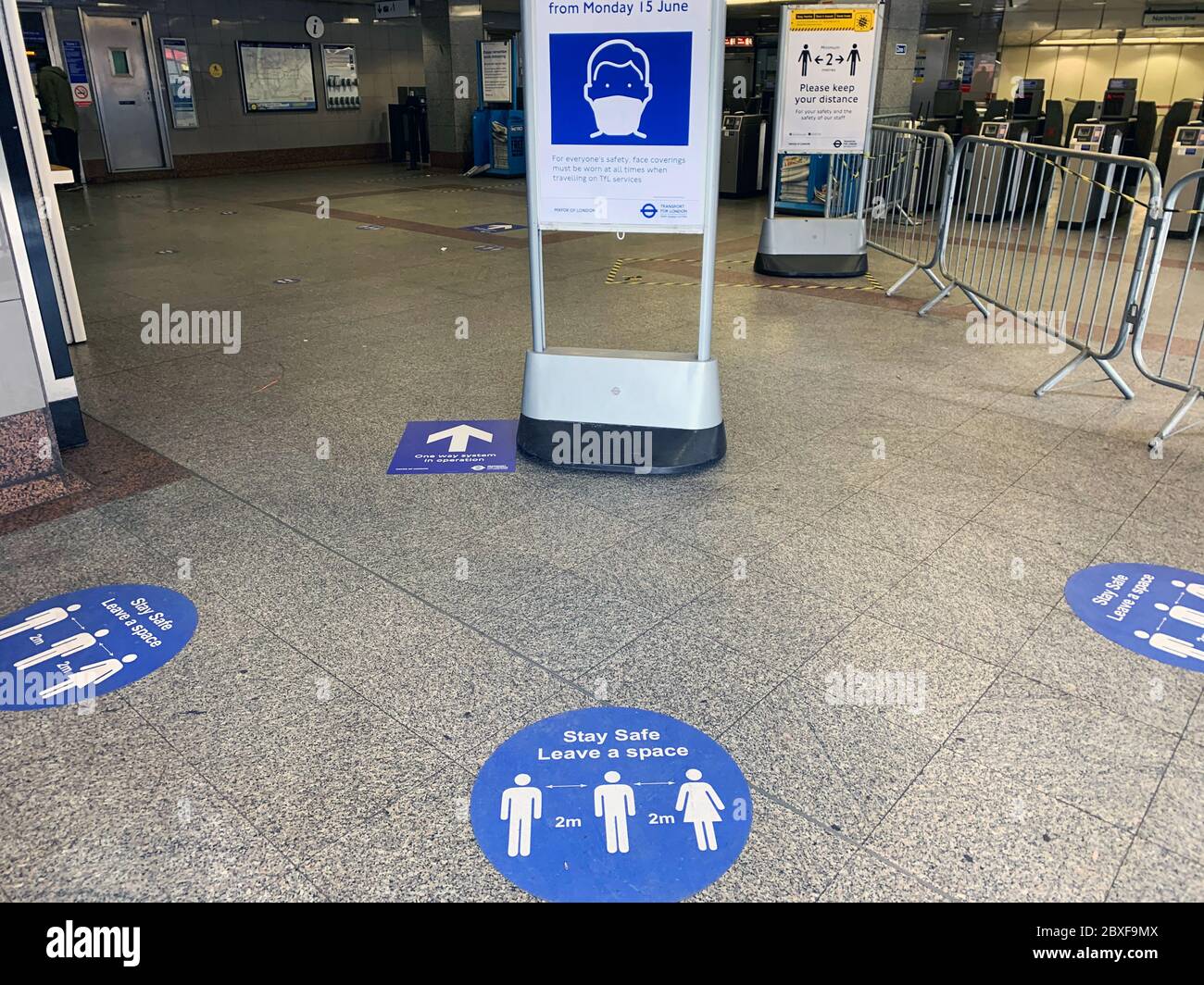 London unterirdisch während der Coronavirus-Pandemie. Schilder, die die Bedeutung sozialer Distanz und die Notwendigkeit, eine Gesichtsbedeckung ab dem 15. Juni 2020 zu tragen, zeigen. Stockfoto