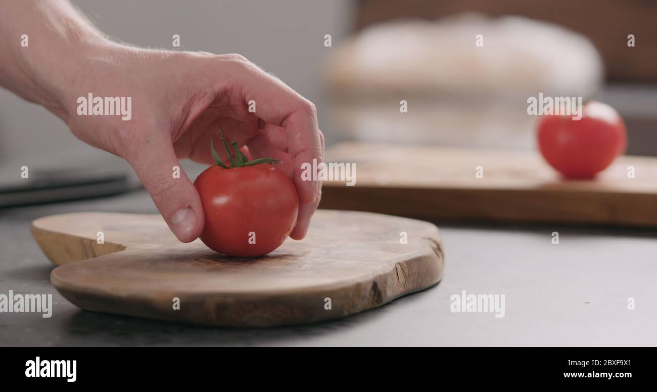 Mann legte frische rote Tomate auf Olivenbrett Seitenansicht Stockfoto