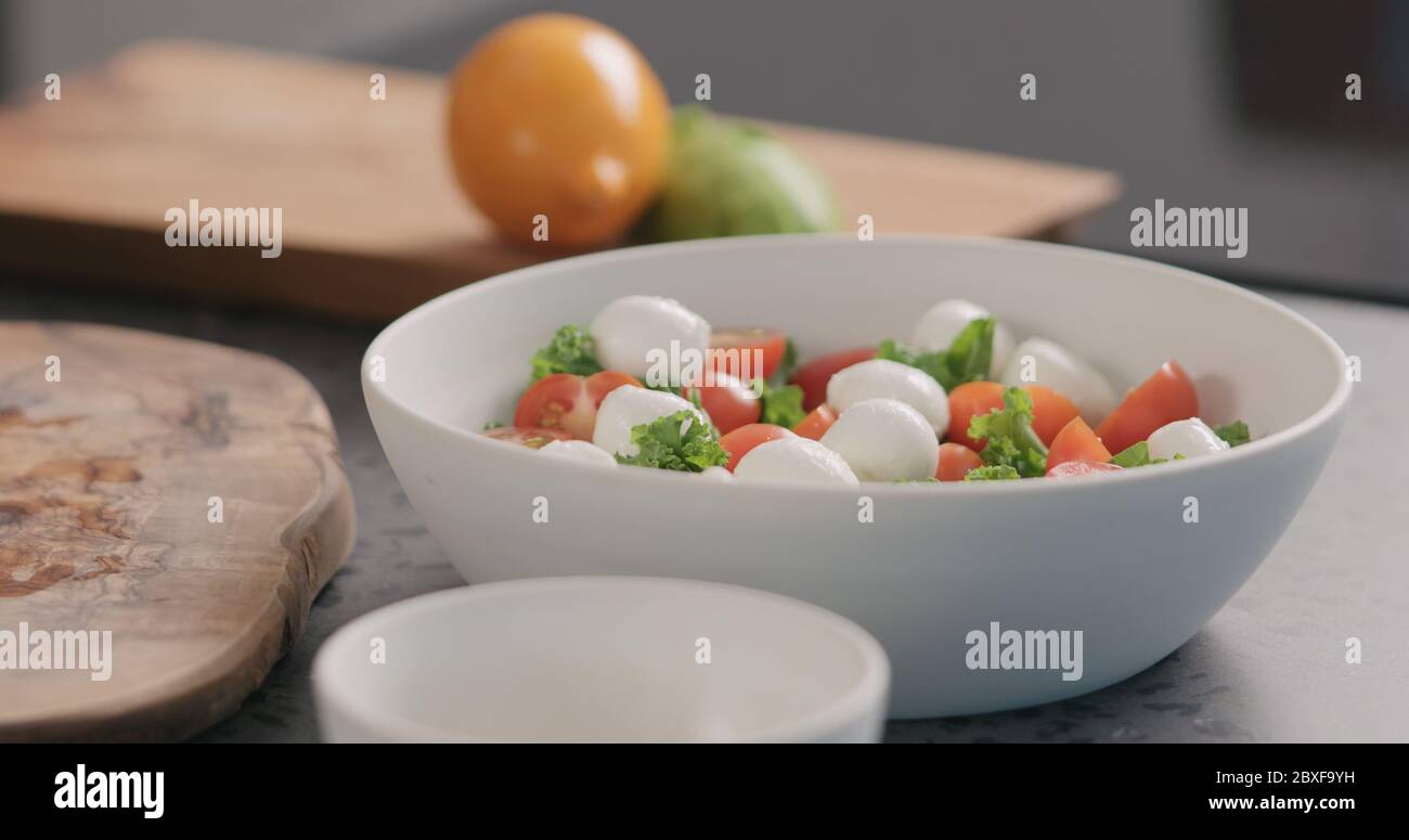 Mozzarella in Salat mit Grünkohl und Tomaten in weiß geben Schüssel auf Küchenarbeitspe Stockfoto