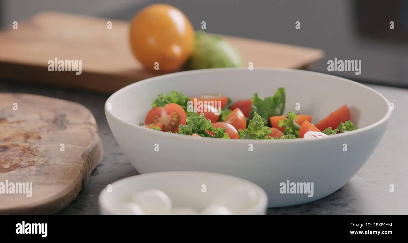 Tomaten in Salat mit Grünkohl und in einer weißen Schüssel geben Auf der Küchenarbeitsfläche Stockfoto