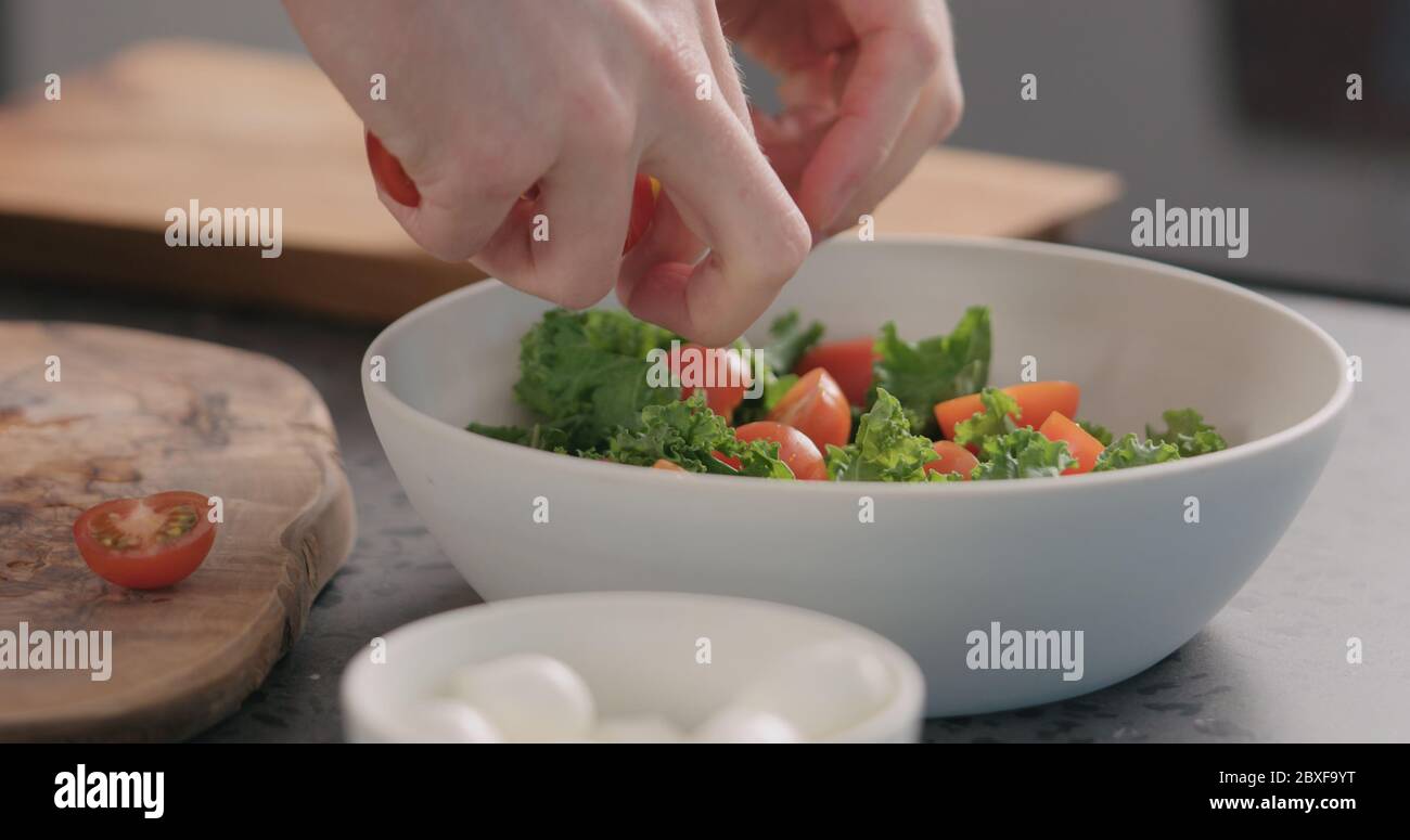 Man Tomaten in Salat mit Grünkohl und in weiß Schüssel auf Küchenarbeitspe Stockfoto