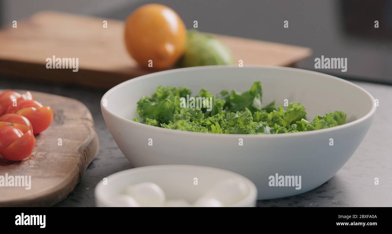 Tomaten in Salat mit Grünkohl und in einer weißen Schüssel geben Auf der Küchenarbeitsfläche Stockfoto