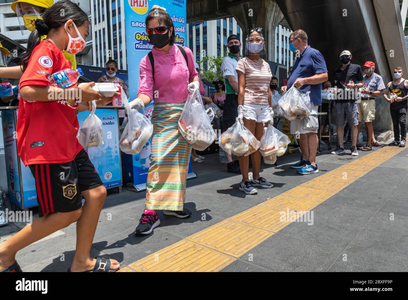 Freiwillige mit Gesichtsmaske und Handschuhen, die während der Covid-Pandemie in Bangkok, Thailand, kostenloses Essen bei der Food Bank geben Stockfoto
