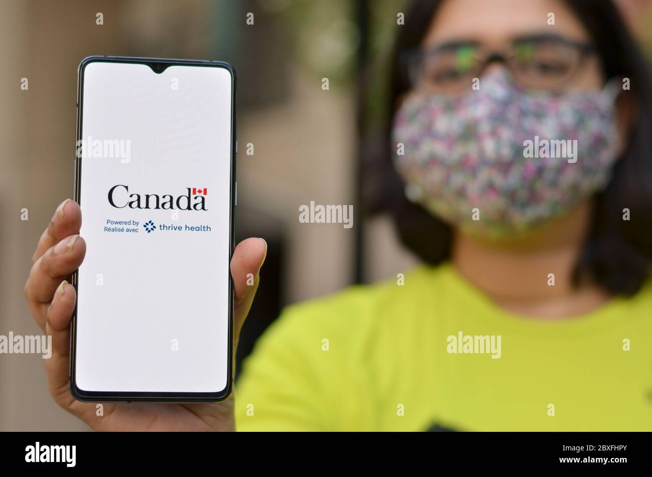 Toronto, Ontario, Kanada, 2020. Mädchen trägt Gesichtsmaske zeigt Covid-19 App auf dem Handy. Health Canada in Partnerschaft mit Thrive Health hat geschaffen Stockfoto