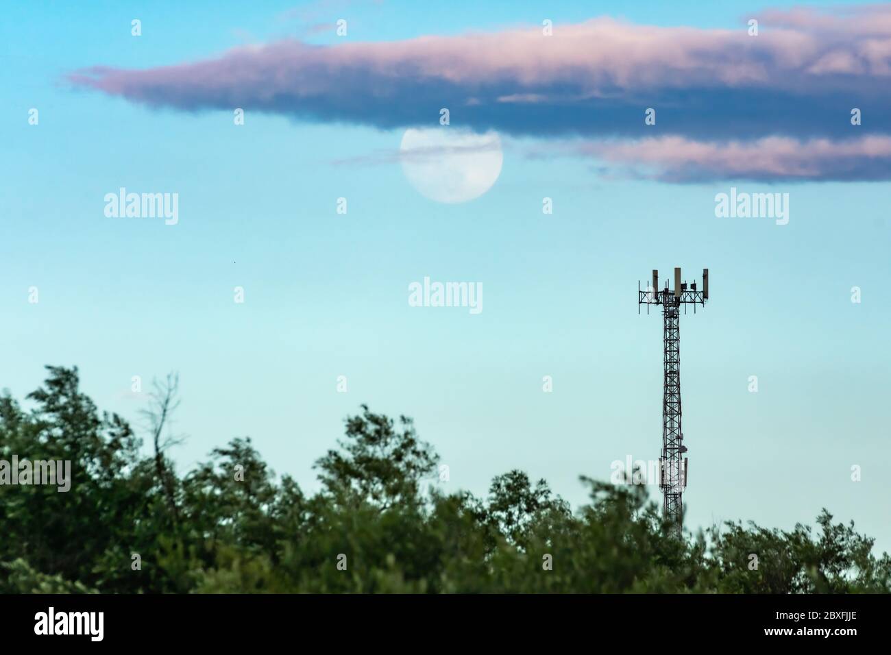 Turm mit Handy-Antennen oder Repeater mit Vollmond im Hintergrund Stockfoto