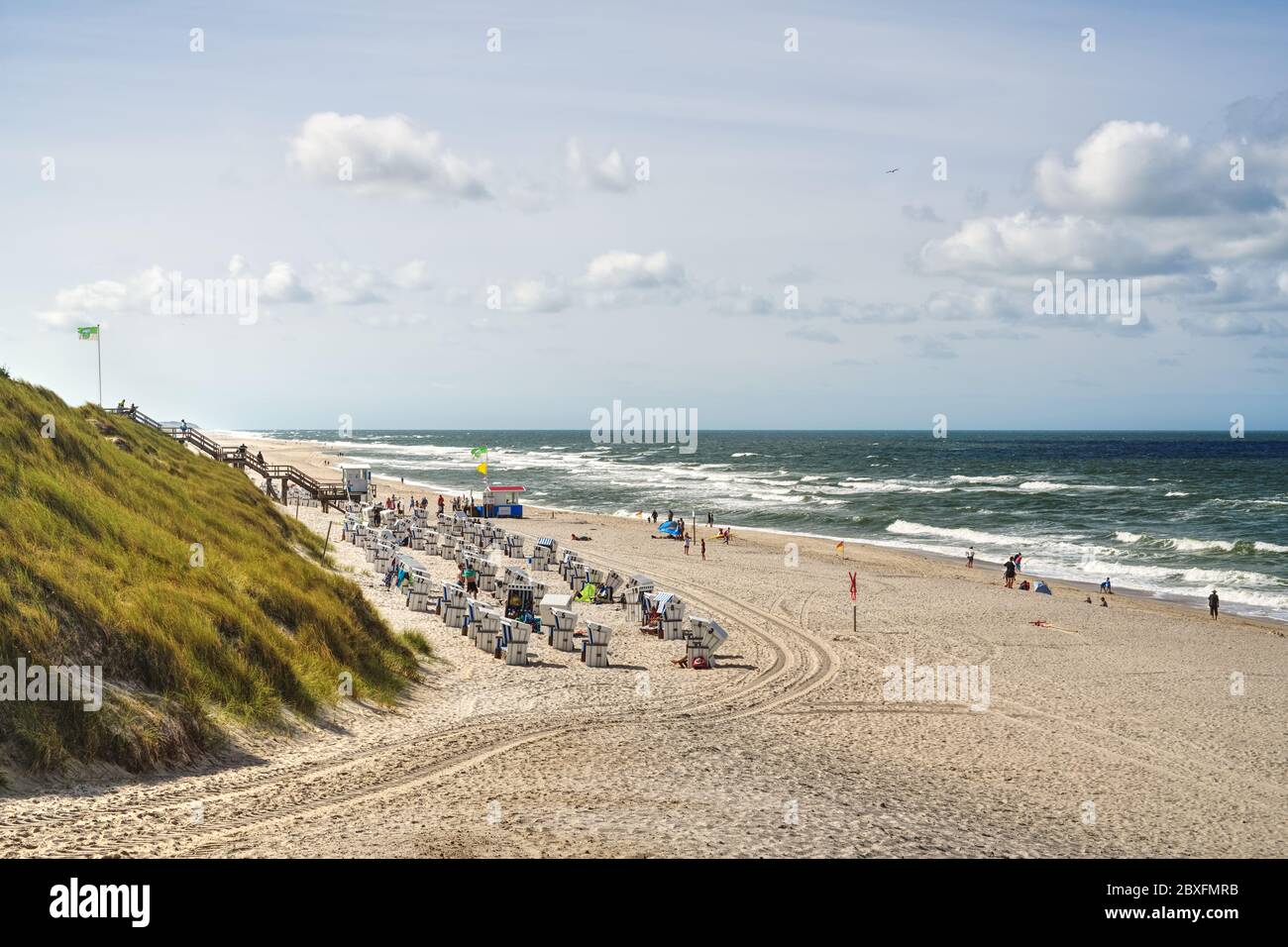 Blick auf Sylter Strand mit Dünen, Liegen und der Nordsee. Typische Strandlandschaft mit Urlaubern im Sommer auf der deutschen Wattenmeerinsel. Stockfoto
