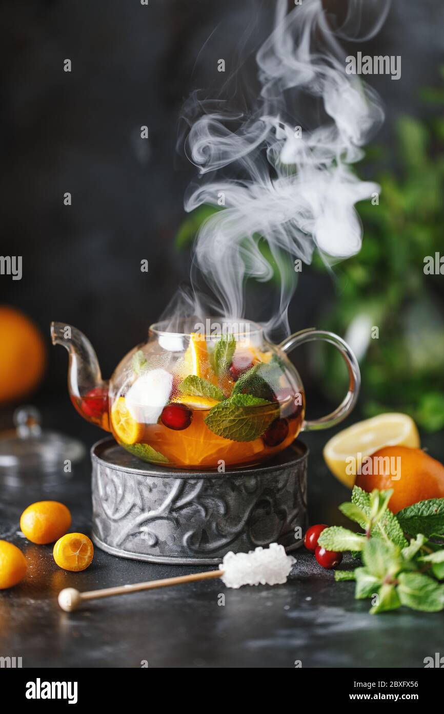 Früchtetee mit Minze, Orangen und Preiselbeere auf dunklem Steingrund. Eine Tasse heißen Tee Stockfoto
