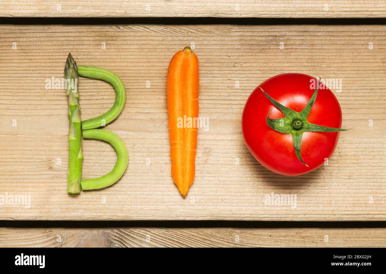 Das Wort 'Bio' geschrieben mit Gemüse auf rustikalem Holzhintergrund, Konzept - Bio-Zutaten für gesunde vegane Lebensmittel und Lifestyle. Stockfoto