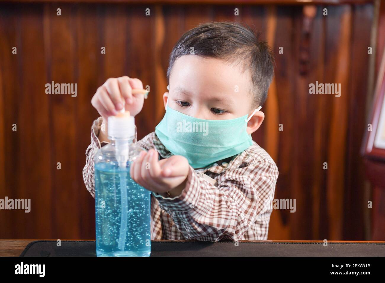 Junge, die eine chirurgische Maske mit Handdesinfektionsmittel trägt Stockfoto