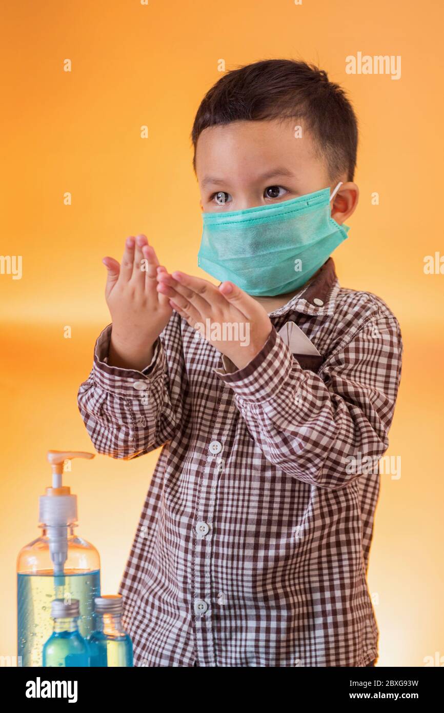 Junge, die eine chirurgische Maske mit Handdesinfektionsmittel trägt Stockfoto