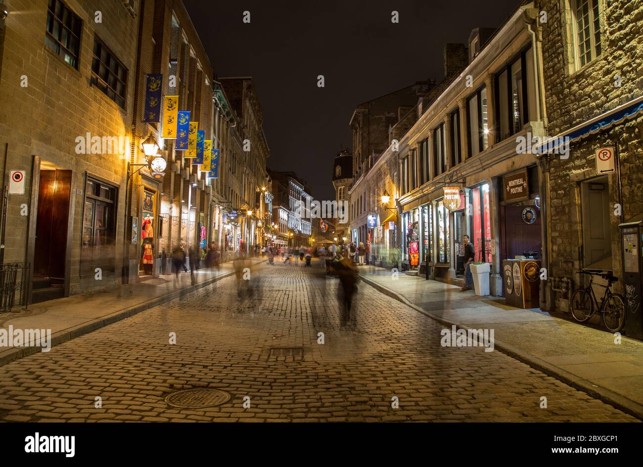 MONTREAL, KANADA - 17. MAI 2015: Gebäude und Geschäfte entlang der Rue Saint Paul in der Altstadt von Montreal bei Nacht. Die Unschärfe der Menschen ist zu sehen. Stockfoto