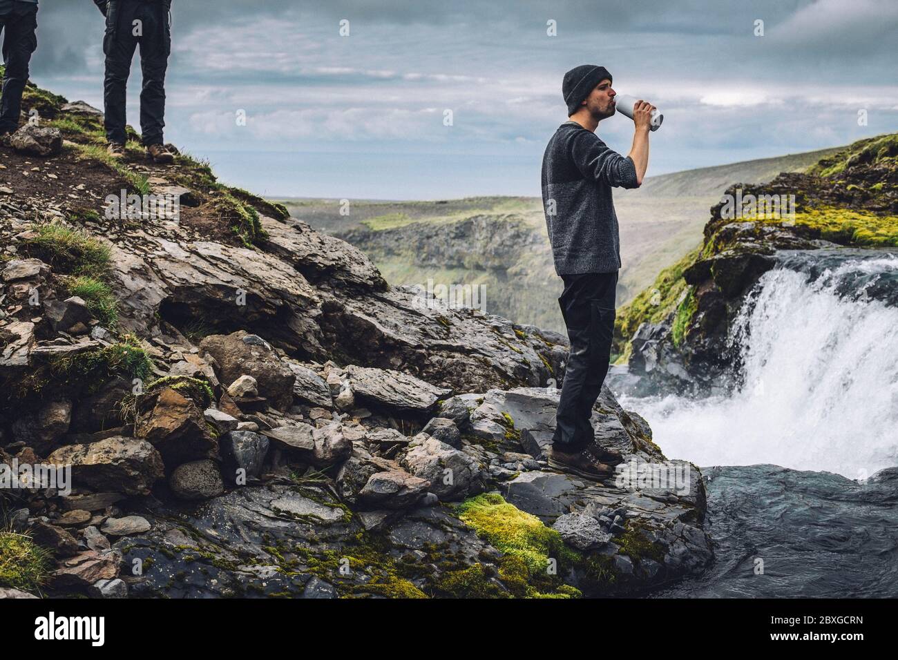 Mann, der frisches Wasser aus einem Fluss in der Nähe von Landmannalaugar, Fjallabak Nature Reserve, Süd-Zentral-Island, Island trinkt Stockfoto