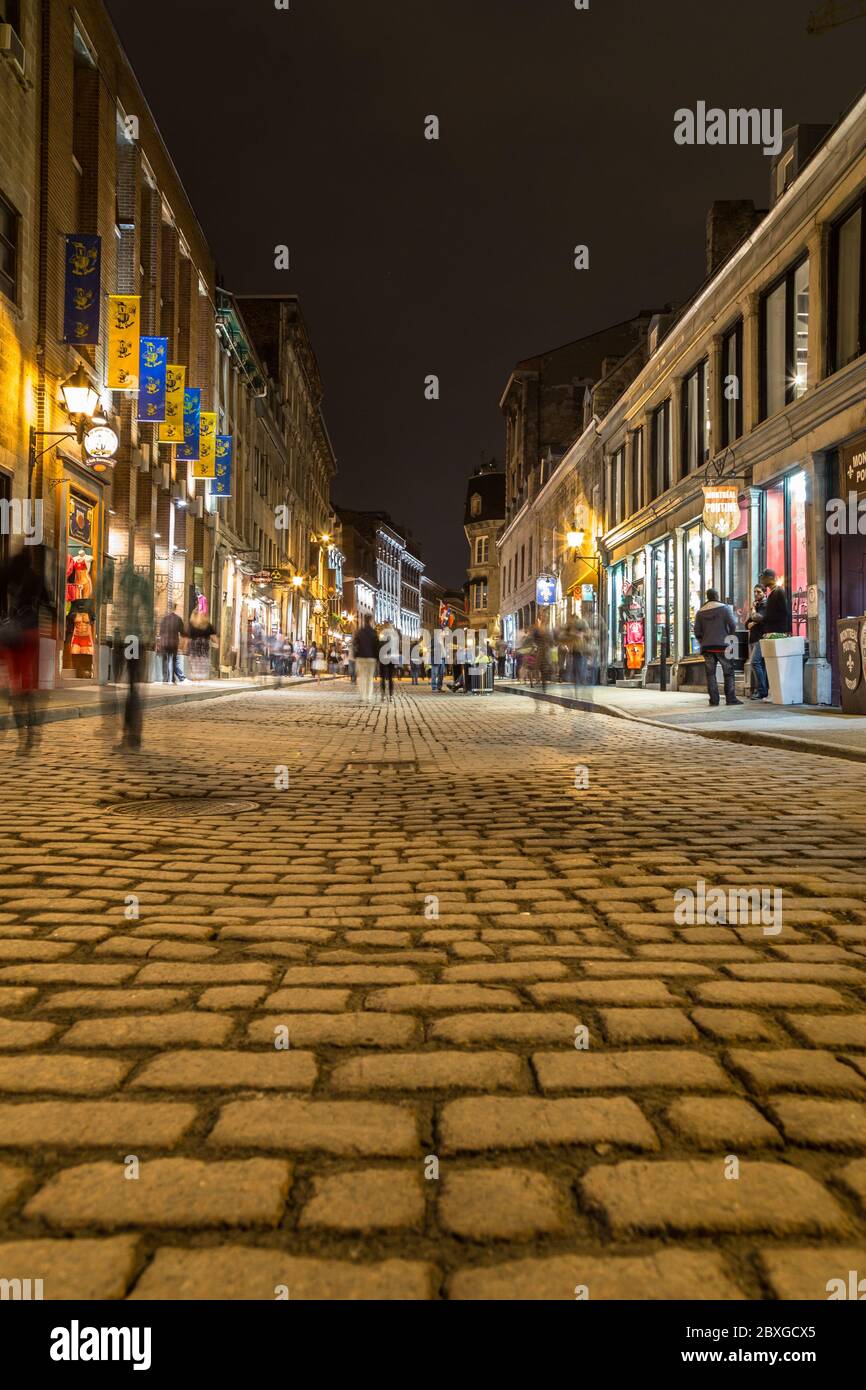 MONTREAL, KANADA - 17. MAI 2015: Gebäude und Geschäfte entlang der Rue Saint Paul in der Altstadt von Montreal bei Nacht. Die Unschärfe der Menschen ist zu sehen. Stockfoto