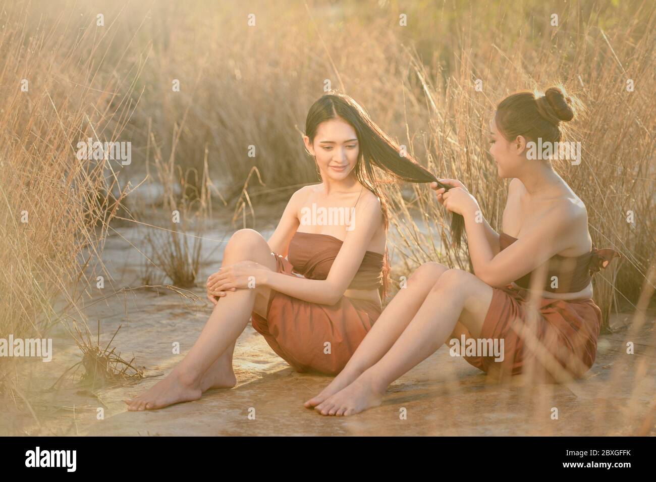Frau am Strand sitzend, die mit den Haaren ihres Freundes bezahlt, Thailand Stockfoto