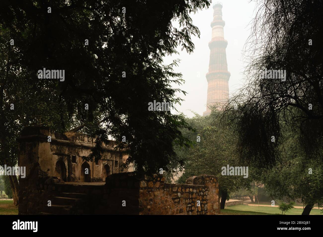 Dawn hebt über das Gelände des Qutb Minar Komplex und Ruinen an nebligen Morgen in Delhi, Indien. Stockfoto
