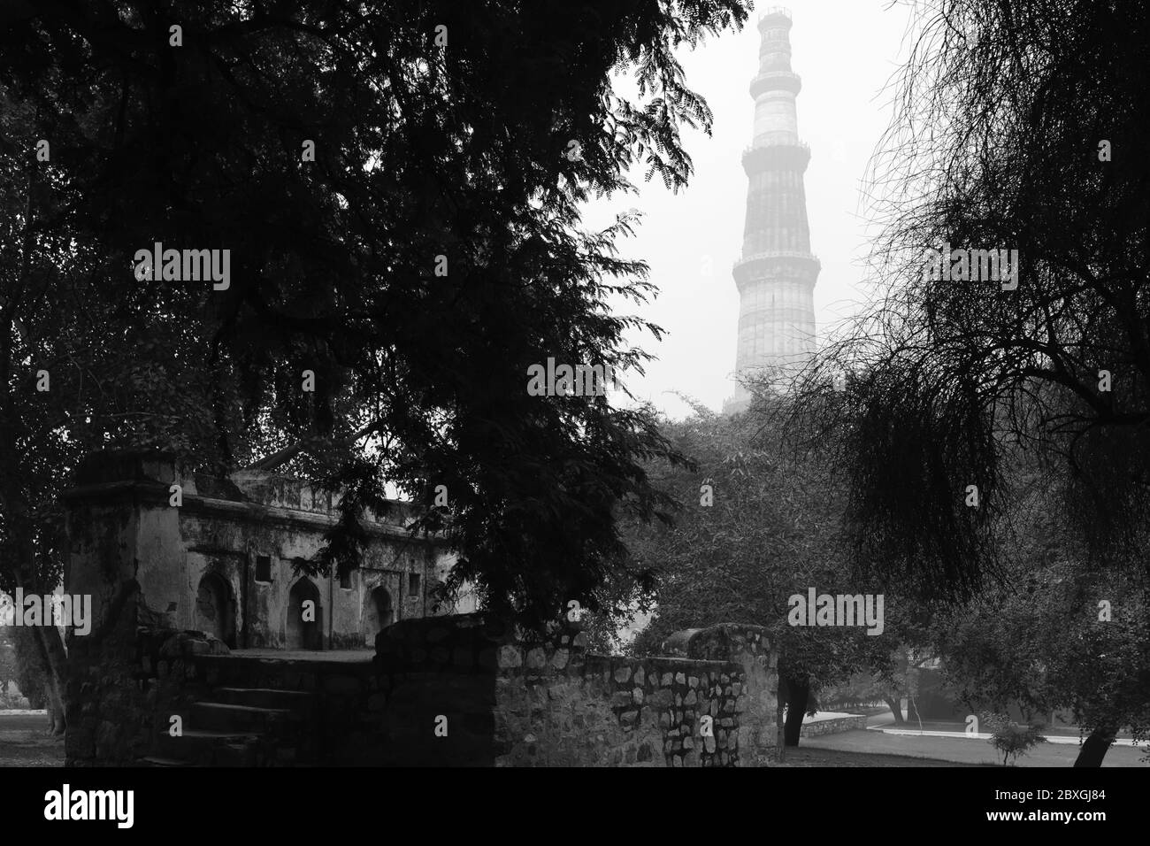 Dawn hebt über das Gelände des Qutb Minar Komplex und Ruinen an nebligen Morgen in Delhi, Indien. Stockfoto