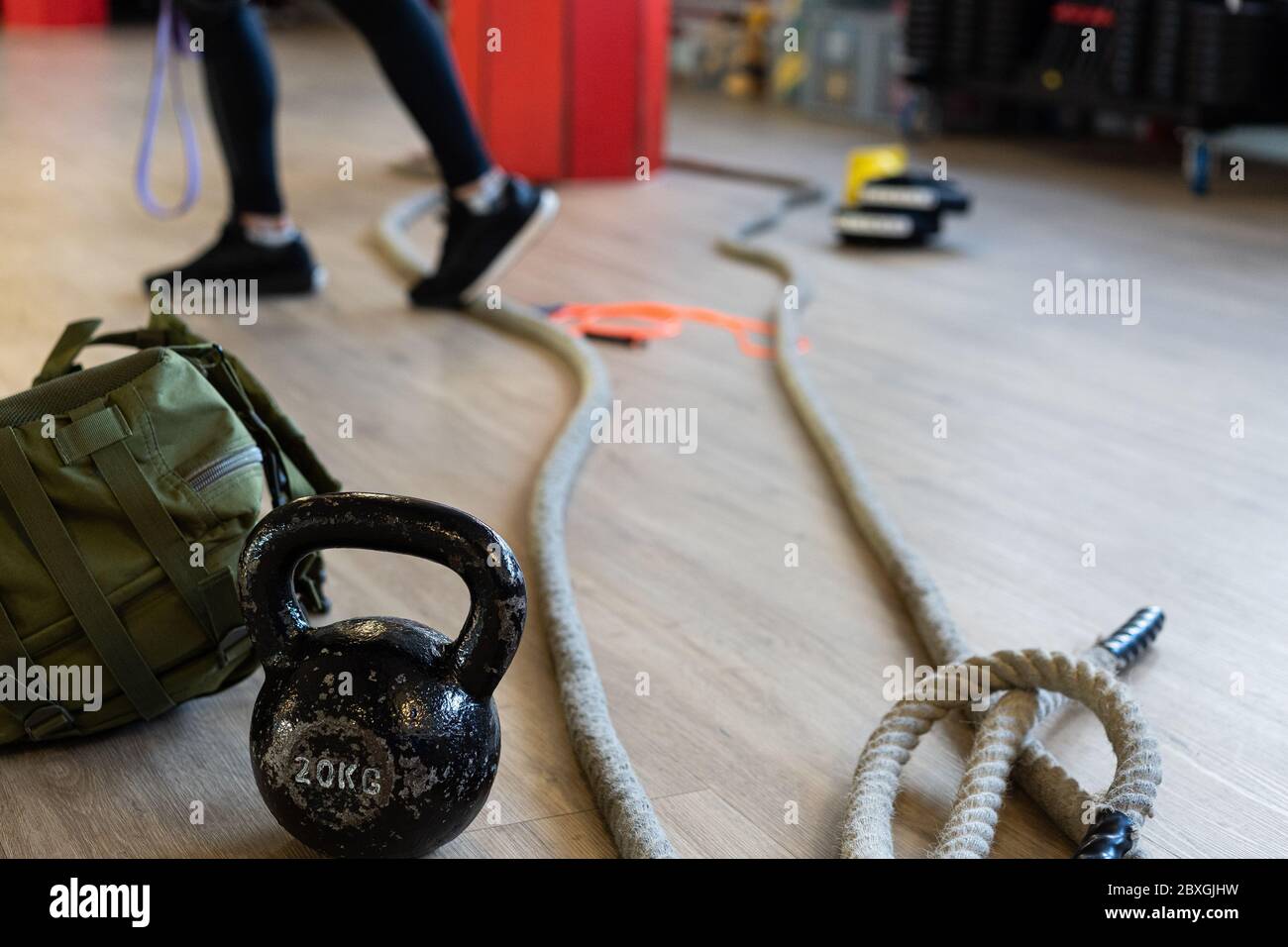 Fitnessgeräte für Boot Camp und trainieren mit Wasserkocher Glocke, Seil, Sandsack in Turnhalle auf dem Boden. Beine des Instruktors im Hintergrund. Stockfoto