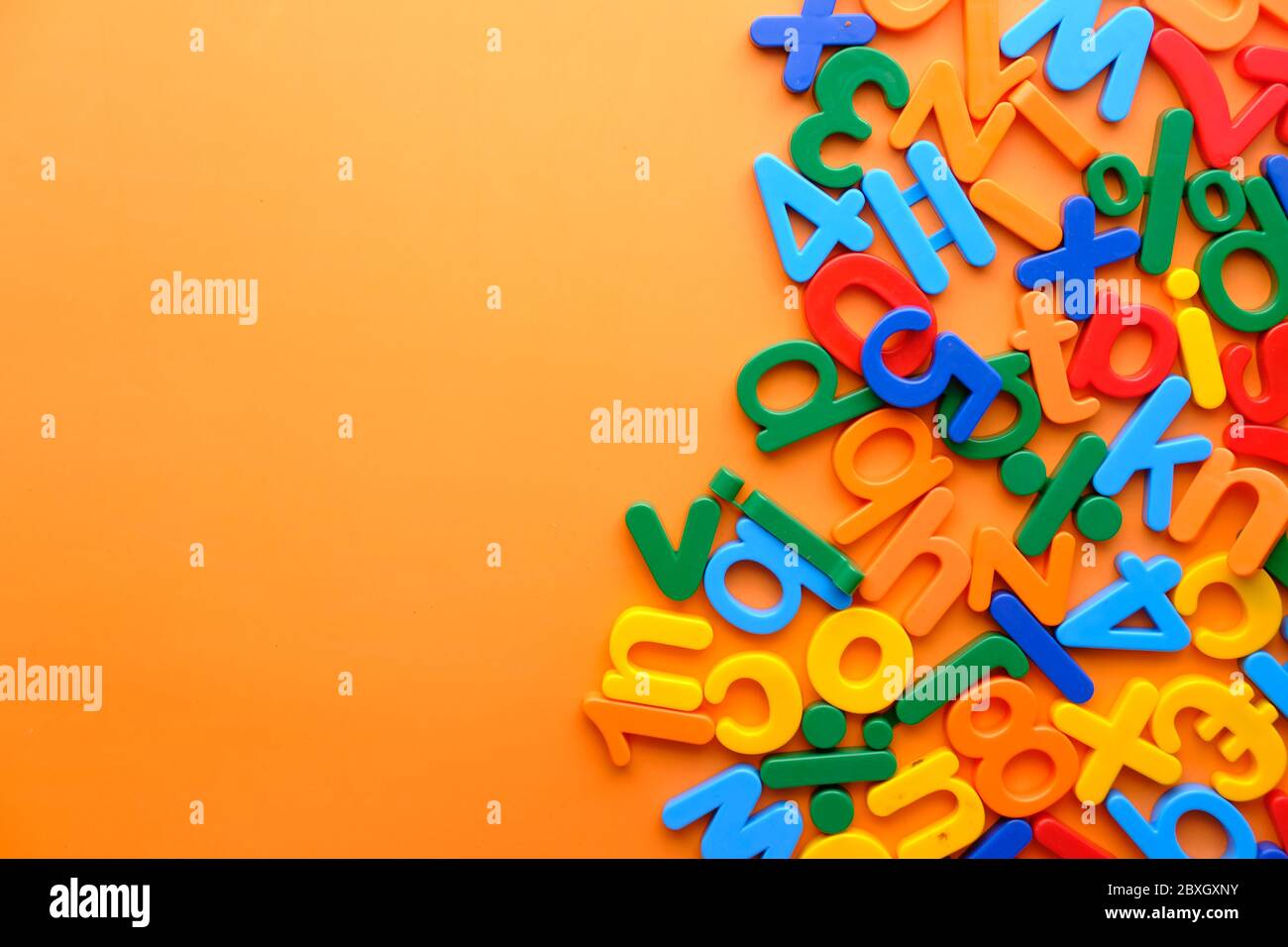 Bunte Plastikbuchstaben auf orangefarbenem Hintergrund, Draufsicht Stockfoto