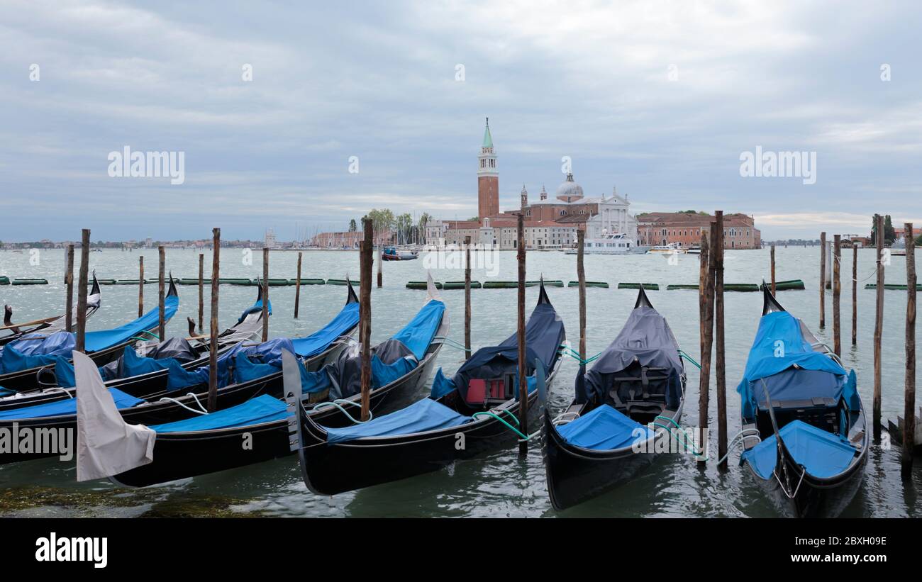 Eine Reihe von Gondeln und die Kirche San Giorgio Maggiore auf der Insel Saint Giorgio Maggiore im Hintergrund, Venedig, Italien Stockfoto
