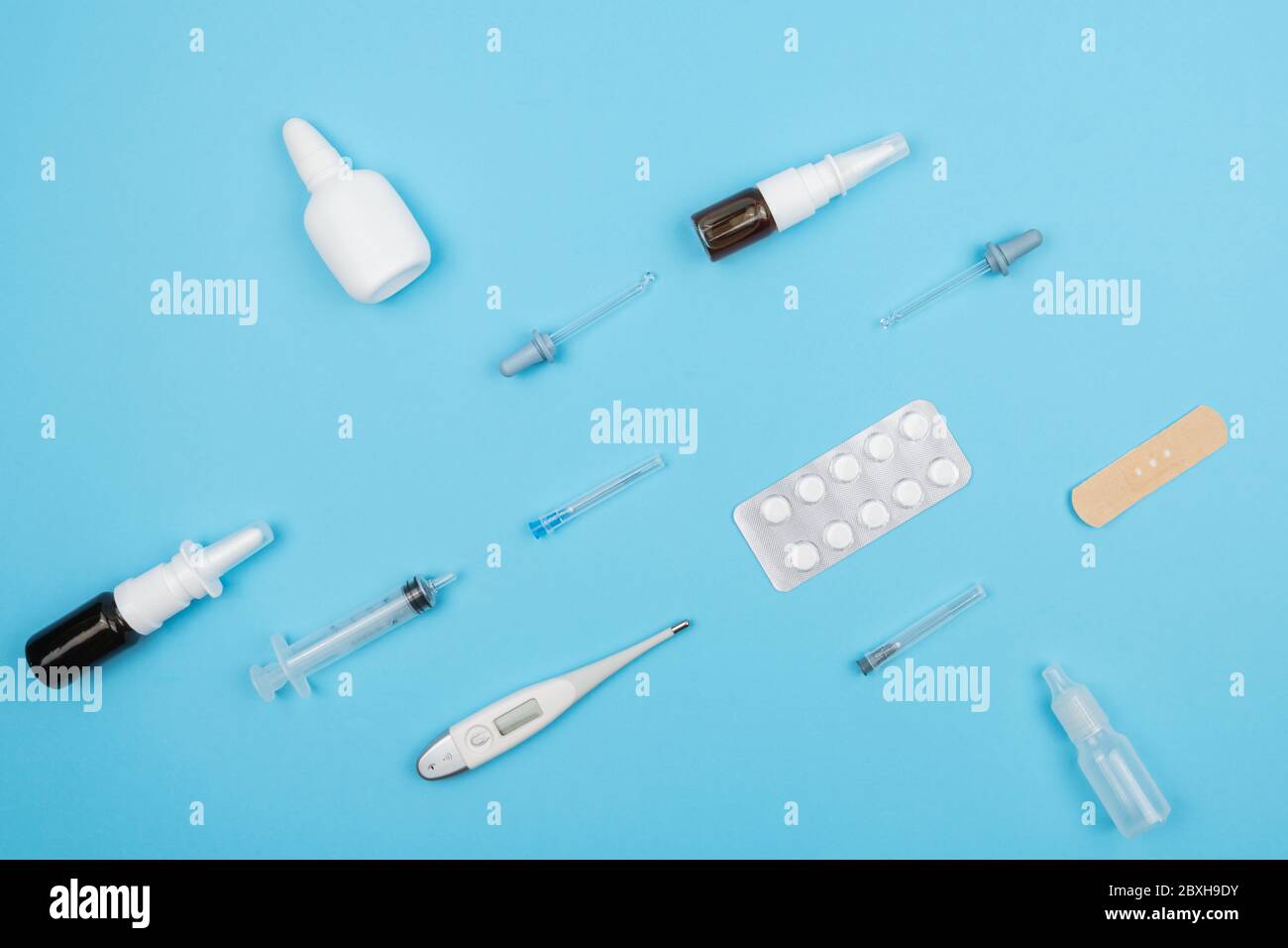 Medikamente zur Behandlung von Erkältungen auf blauem Hintergrund. Pillen und Pillenflaschen, Spritzen und Thermometer. Stockfoto