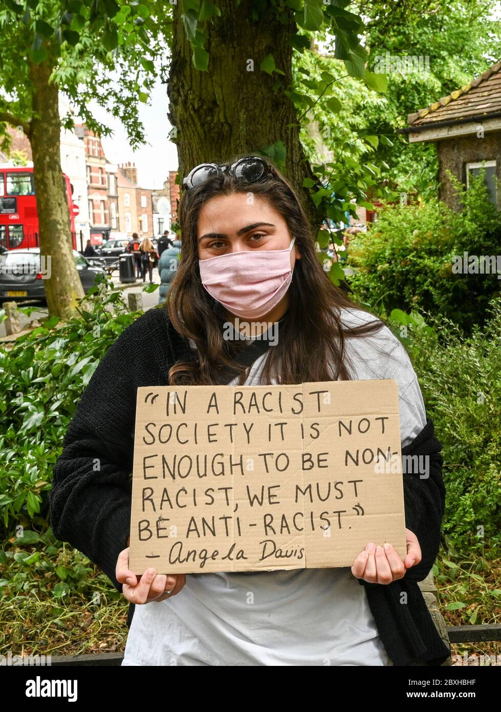 Eine junge Frau mit einem Plakat, die Angela Davis zitiert: "In einer rassistischen Gesellschaft reicht es nicht aus, nicht-rassistisch zu sein, wir müssen antirassistisch sein." Schwarze Leben sind wichtig. Stockfoto