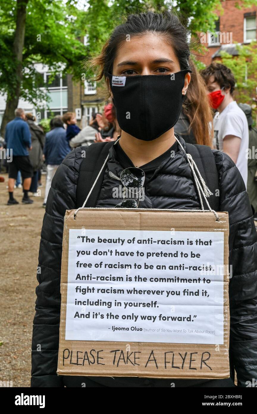 Eine junge Frau in einer Maske mit einem Plakat über Anti-Rassismus bei einer Demonstration zur Unterstützung von 'Black Lives Matter'. London, Großbritannien. Stockfoto