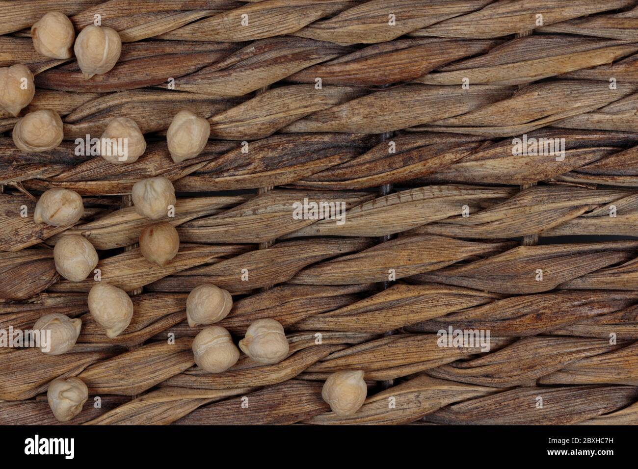Verstreute, trockene Garbanzo-Bohnen oder Kichererbsen auf braunem, Weidenhintergrund mit Kopierraum Stockfoto