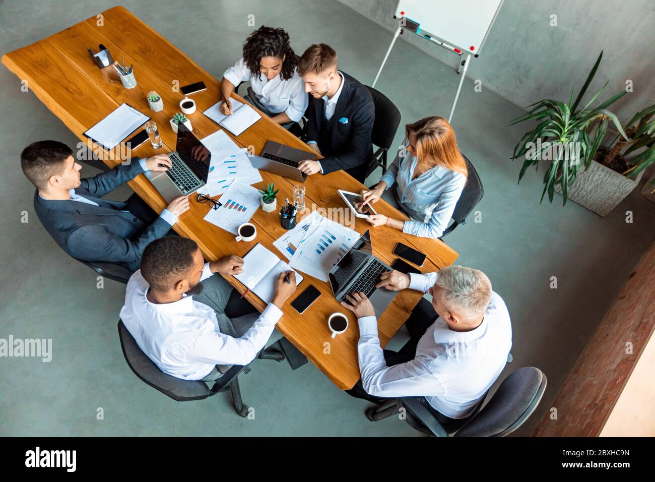 Mitarbeiter, Die An Einem Schreibtisch Arbeiten, Indem Sie Gadgets Im Büro Verwenden Stockfoto