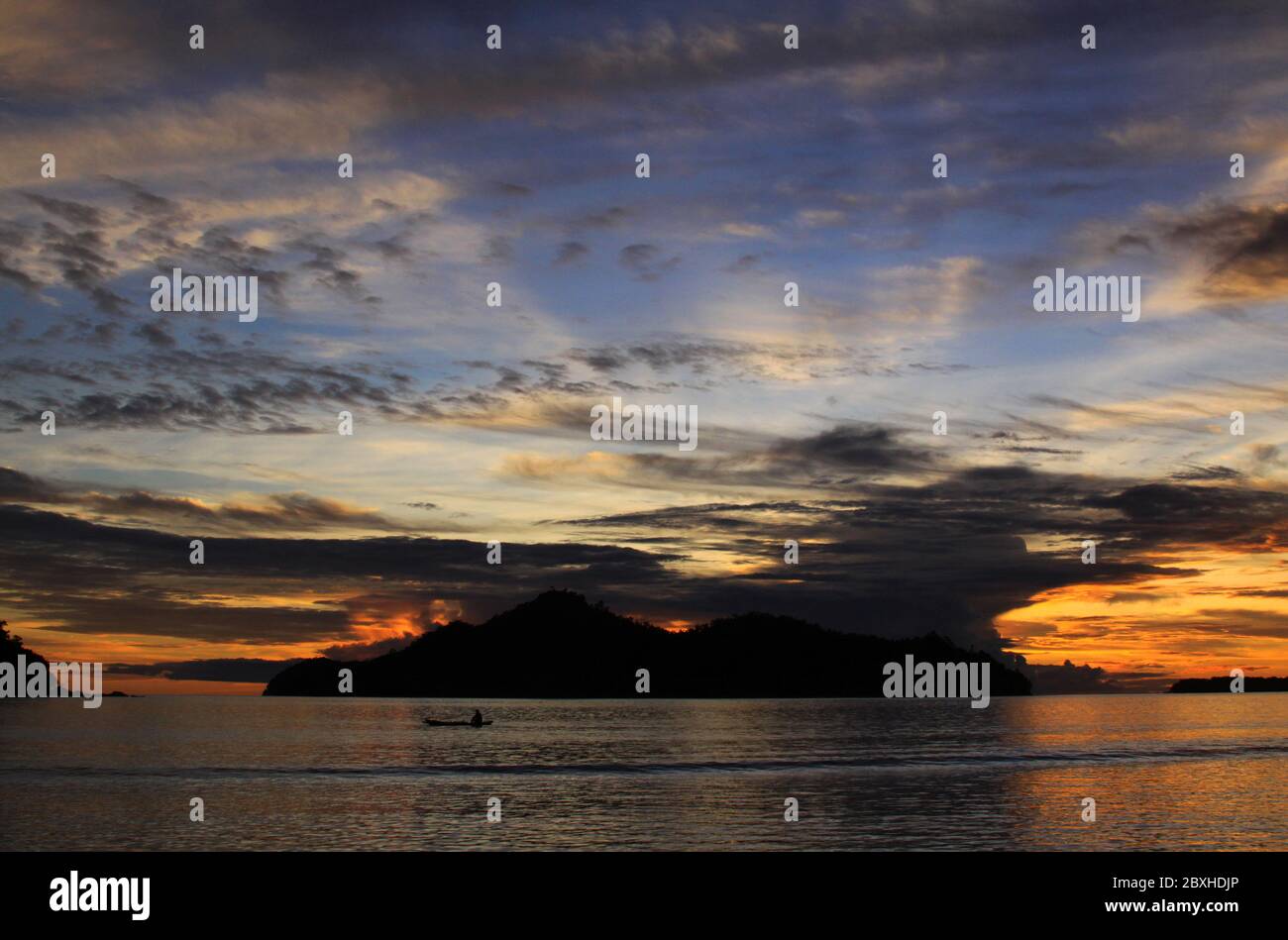 Boot bei Sonnenuntergang mit Sonnenstrahlen den Himmel beleuchten, von hinten Wolken auf Marak Insel, gesehen von in Pasumpahan Insel, Sumatra, Indonesien Stockfoto