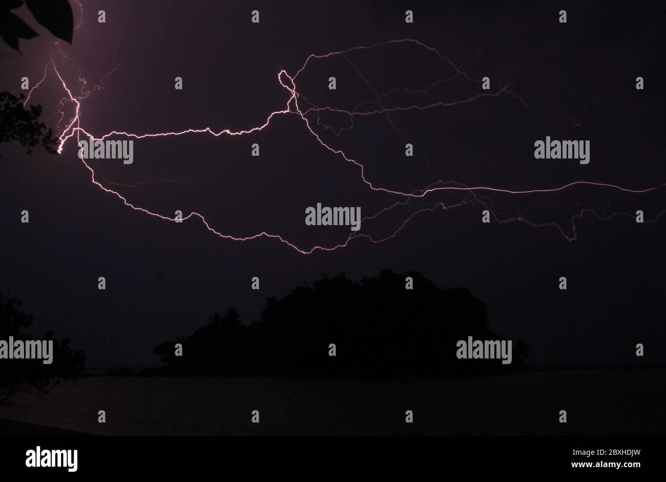 Insel Silhouette und Blitz während der Nacht Sturm. Fast schwarzes Nachtbild mit elektrisierenden Gewitterlichtern Stockfoto