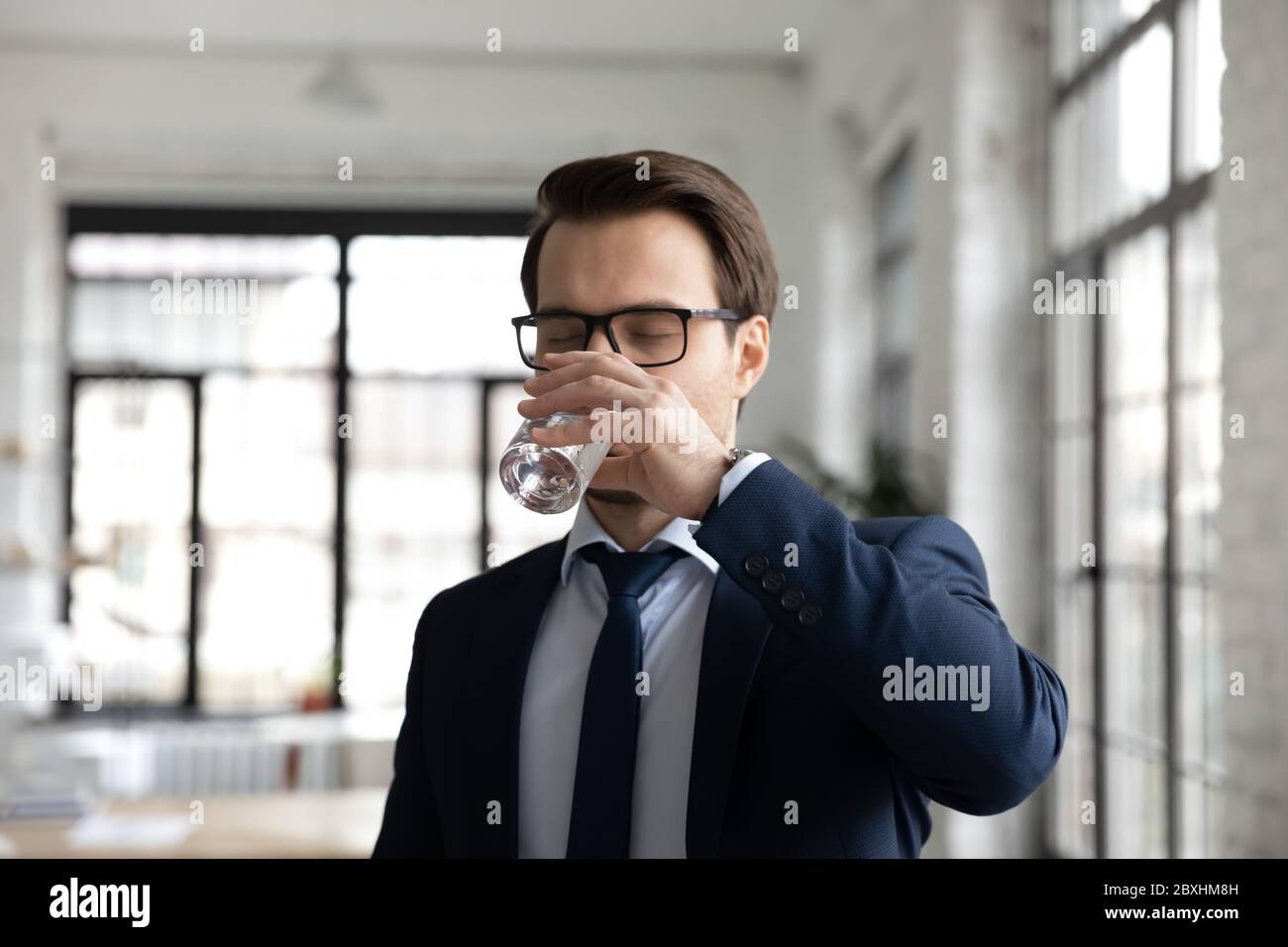 Durstiger männlicher Mitarbeiter trinkt sauberes Mineralwasser Stockfoto